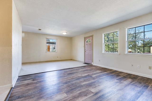 empty room with dark hardwood / wood-style flooring and a textured ceiling