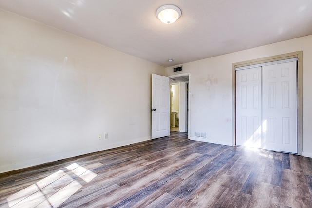 unfurnished bedroom featuring dark hardwood / wood-style flooring, a closet, and a textured ceiling