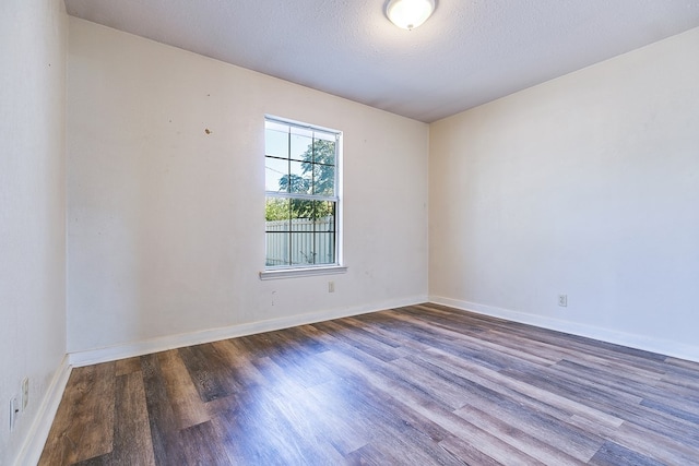 unfurnished room with dark hardwood / wood-style floors and a textured ceiling