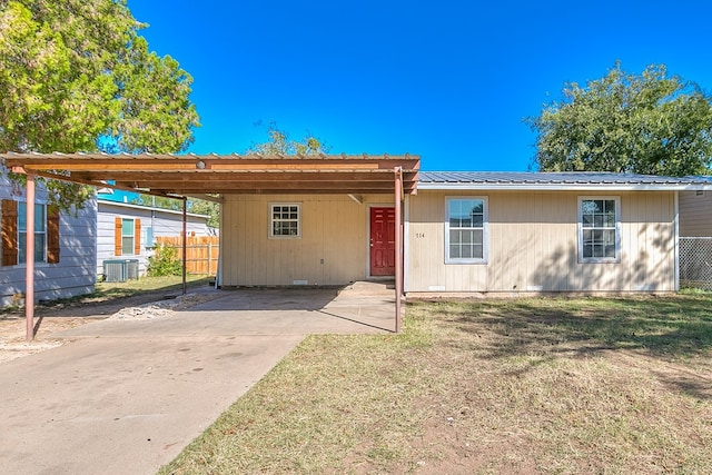 view of front facade with a front yard, a carport, and central air condition unit