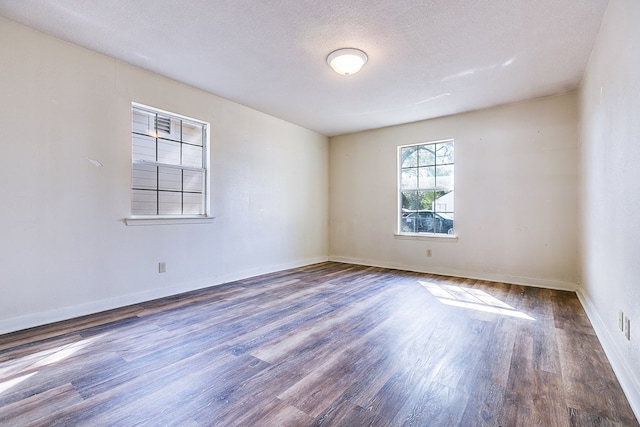 spare room featuring dark hardwood / wood-style floors and a textured ceiling