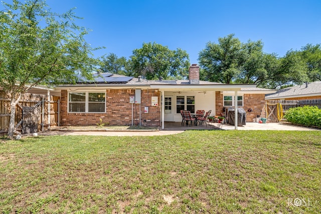 2713 Canyon Creek Dr, San Angelo, TX 76904 - back of house featuring a chimney, roof mounted solar panels, brick siding, a ceiling fan, and a patio