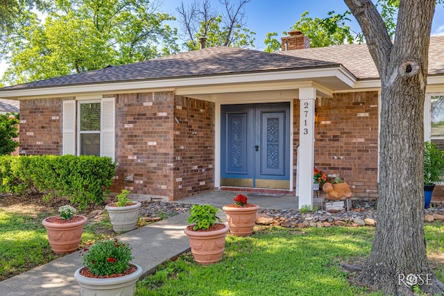 2713 Canyon Creek Dr, San Angelo, TX 76904 - property entrance featuring brick siding, a chimney, and roof with shingles