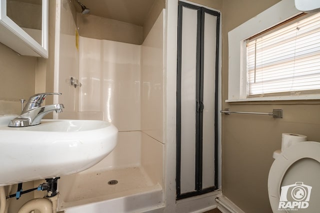 bathroom with walk in shower, toilet, and sink