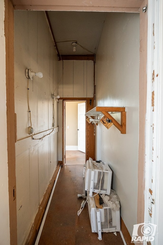 hallway featuring a wall mounted air conditioner, concrete floors, and wood walls