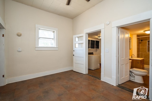 unfurnished bedroom with dark wood-type flooring, ensuite bathroom, washer / dryer, and sink