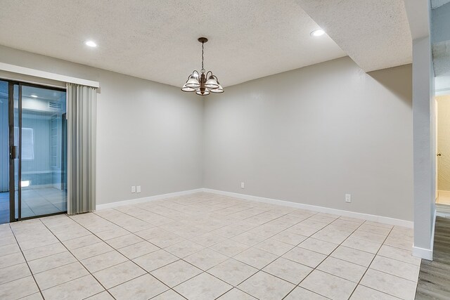 unfurnished room featuring a chandelier, light tile patterned floors, and a textured ceiling