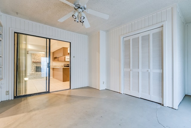 unfurnished bedroom featuring a closet, a textured ceiling, ceiling fan, and wood walls