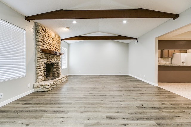 unfurnished living room with lofted ceiling with beams, a fireplace, and light hardwood / wood-style flooring