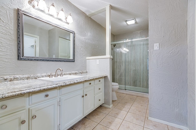 bathroom with vanity, toilet, a shower with shower door, and a textured ceiling