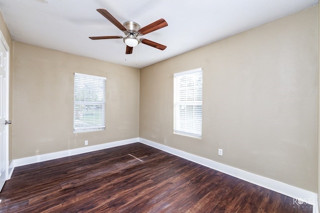 spare room featuring dark wood-style floors, a wealth of natural light, ceiling fan, and baseboards