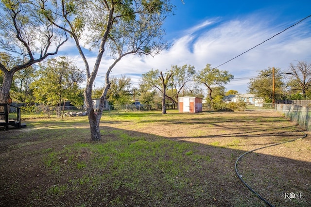 view of yard featuring a storage shed, an outdoor structure, and fence