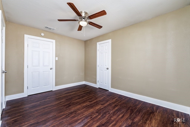 unfurnished room with dark wood-style floors, visible vents, ceiling fan, and baseboards