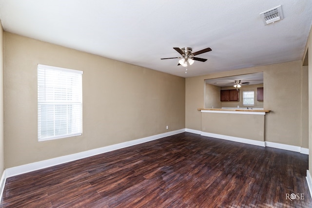 unfurnished living room featuring baseboards, visible vents, ceiling fan, and dark wood-style flooring