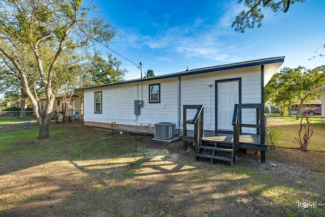 rear view of house featuring a lawn, fence, and central AC