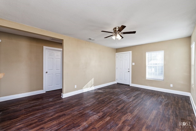 empty room featuring baseboards, visible vents, ceiling fan, and dark wood-type flooring