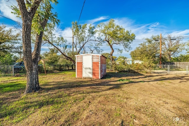 view of yard with a storage shed, fence, and an outbuilding