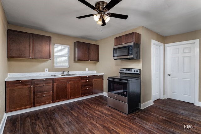 kitchen with baseboards, appliances with stainless steel finishes, dark wood-style flooring, light countertops, and a sink