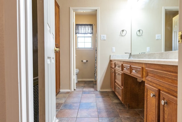 3329 Clearview Dr, San Angelo, TX 76904 - bathroom with toilet, vanity, baseboards, and stone finish flooring