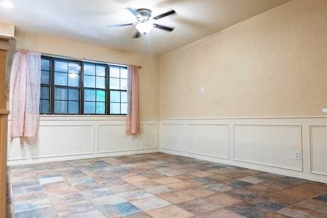 3329 Clearview Dr, San Angelo, TX 76904 - unfurnished room with a decorative wall, stone finish floors, ceiling fan, and a wainscoted wall