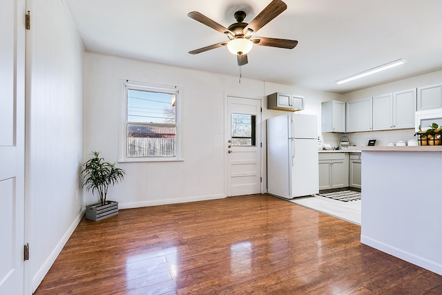 kitchen with white fridge, dark hardwood / wood-style floors, ceiling fan, and decorative backsplash