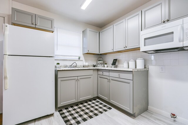 kitchen featuring tasteful backsplash, white appliances, sink, and gray cabinetry