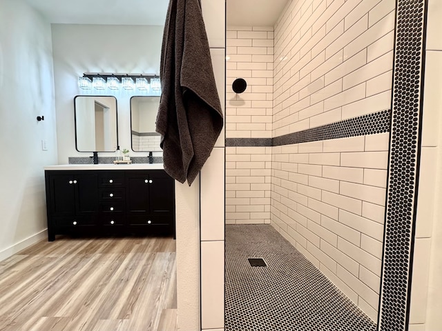 3634 Silver Spur Dr, San Angelo, TX 76904 - full bathroom featuring wood finished floors, double vanity, a tile shower, and baseboards