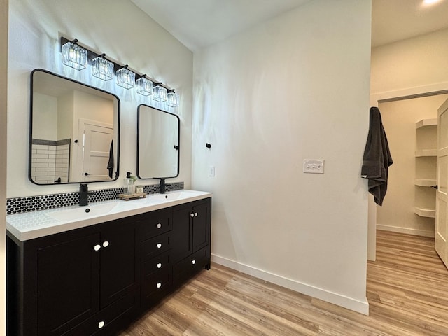 3634 Silver Spur Dr, San Angelo, TX 76904 - full bathroom with baseboards, double vanity, wood finished floors, and decorative backsplash