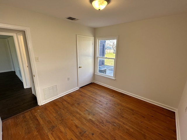 unfurnished bedroom featuring dark wood finished floors, visible vents, and baseboards