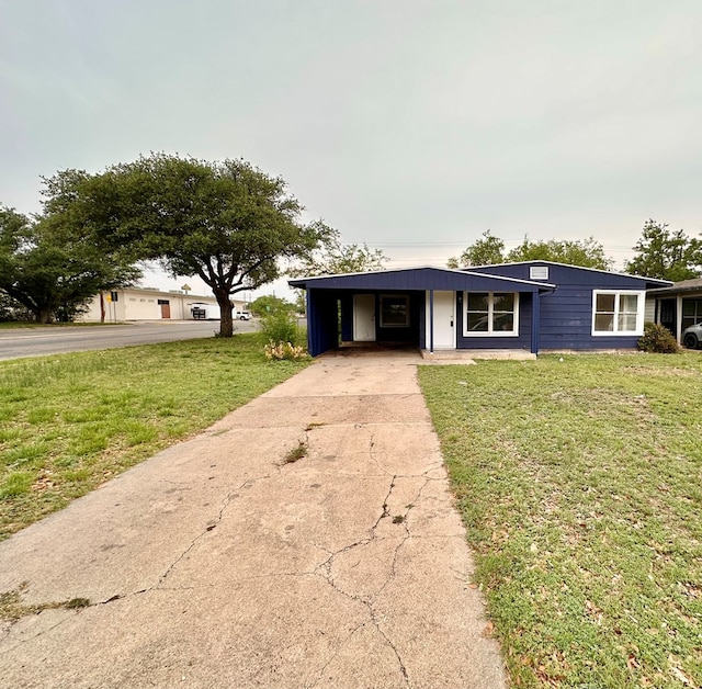 view of front of property featuring concrete driveway, a front yard, and an attached carport