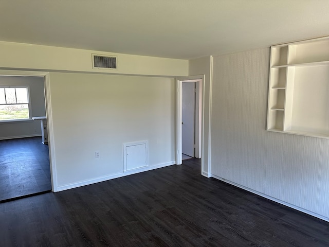 spare room featuring visible vents, baseboards, and dark wood-type flooring