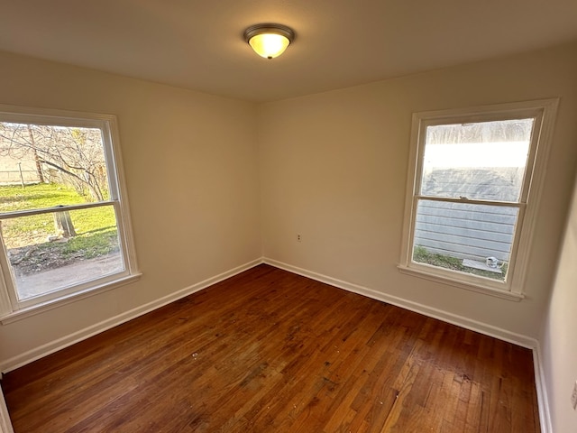 spare room featuring dark wood-style flooring, baseboards, and plenty of natural light