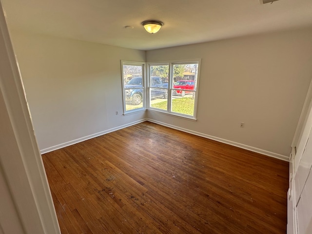 unfurnished room featuring dark wood-type flooring and baseboards