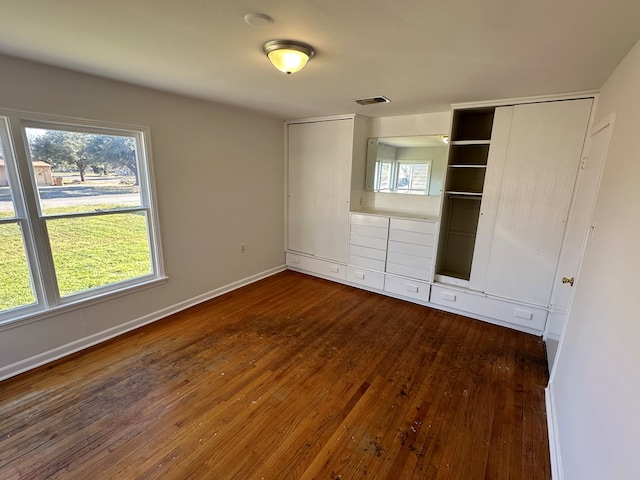 unfurnished bedroom featuring a closet, visible vents, hardwood / wood-style flooring, and baseboards
