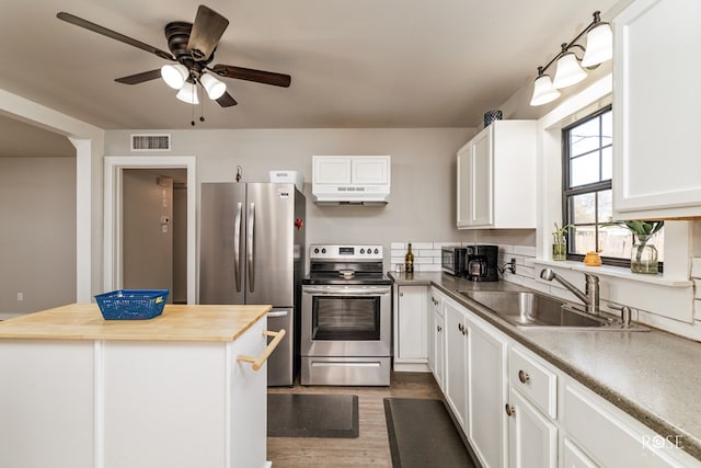 kitchen featuring butcher block counters, under cabinet range hood, appliances with stainless steel finishes, white cabinets, and visible vents