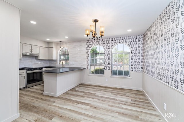 3853 Sandstone Rd, San Angelo, TX 76904 - kitchen featuring stainless steel range with electric stovetop, a peninsula, under cabinet range hood, a chandelier, and dark countertops