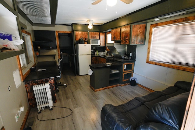 7229 Sun Ln, San Angelo, TX 76901 - kitchen featuring white appliances, dark countertops, ceiling fan, wood finished floors, and radiator