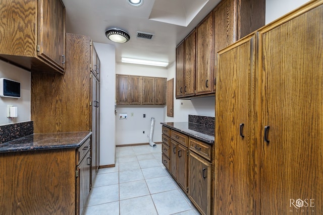 kitchen with light tile patterned floors and dark stone counters