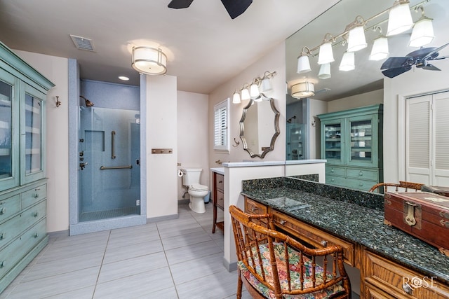 bathroom featuring ceiling fan, toilet, an enclosed shower, and tile patterned flooring