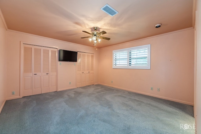 unfurnished bedroom featuring multiple closets, ceiling fan, ornamental molding, and carpet floors