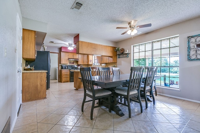 tiled dining room with a textured ceiling and ceiling fan