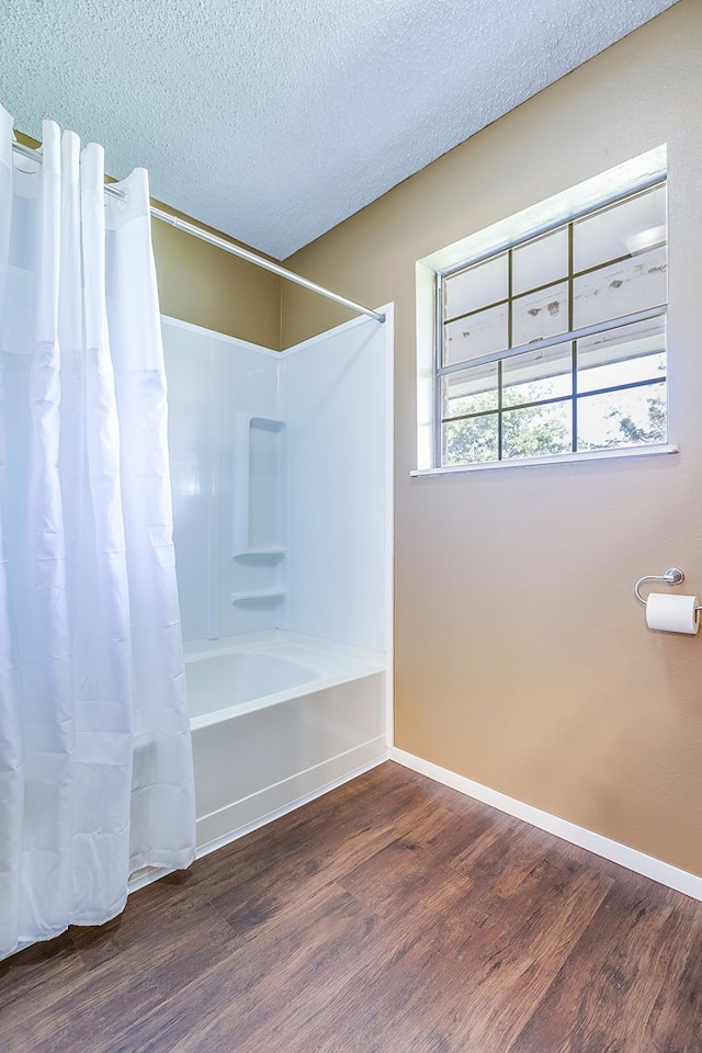 bathroom with shower / tub combo with curtain, hardwood / wood-style floors, and a textured ceiling