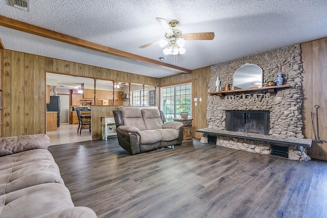 living room with beamed ceiling, wooden walls, and a textured ceiling