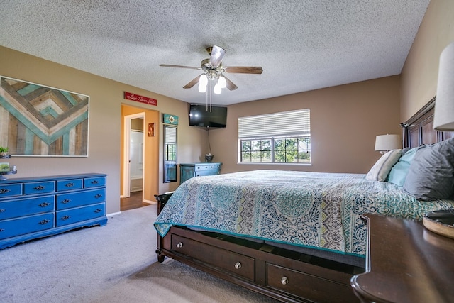 bedroom with ceiling fan, ensuite bath, light carpet, and a textured ceiling