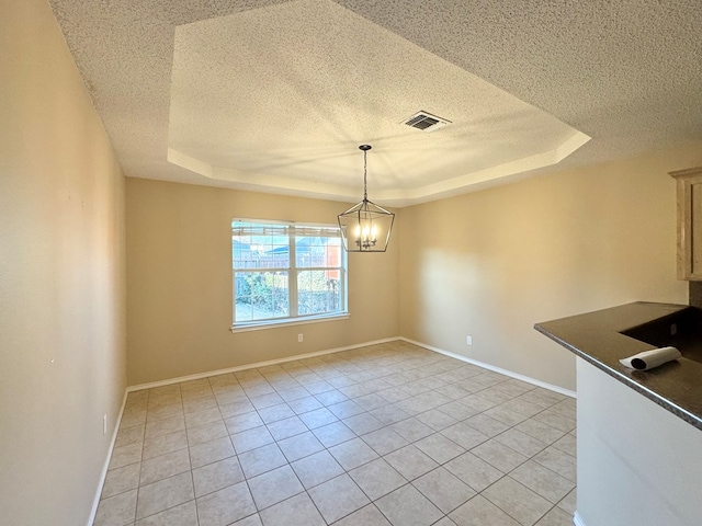 unfurnished dining area with an inviting chandelier, light tile patterned floors, a tray ceiling, and a textured ceiling