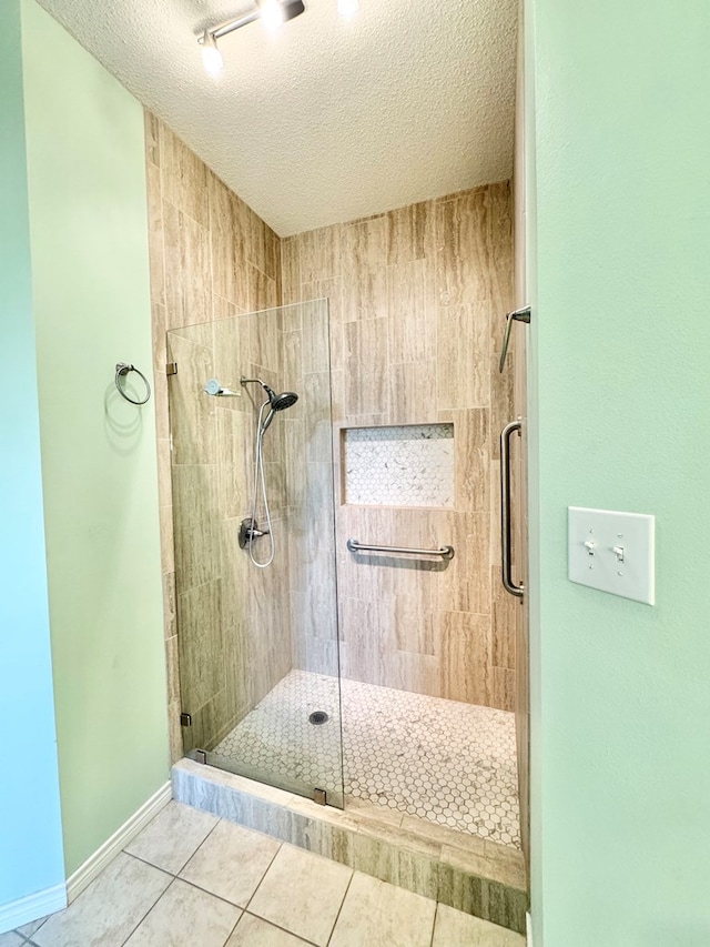 bathroom featuring a shower with door, tile patterned floors, and a textured ceiling