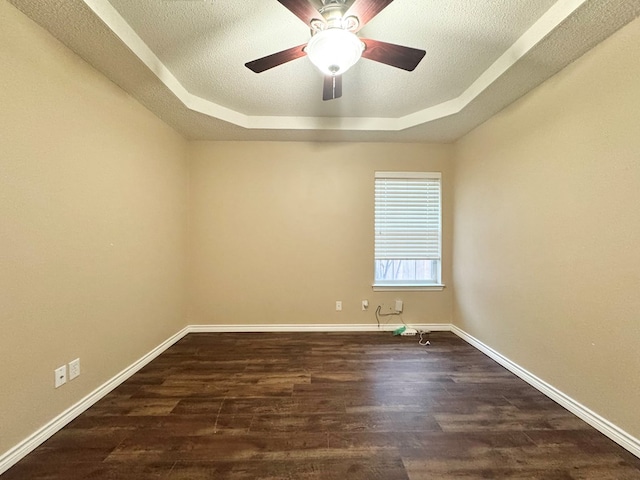 unfurnished room featuring ceiling fan, dark hardwood / wood-style floors, a textured ceiling, and a tray ceiling