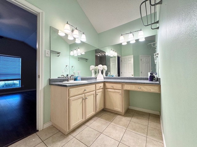 bathroom featuring vanity, lofted ceiling, tile patterned floors, and a textured ceiling