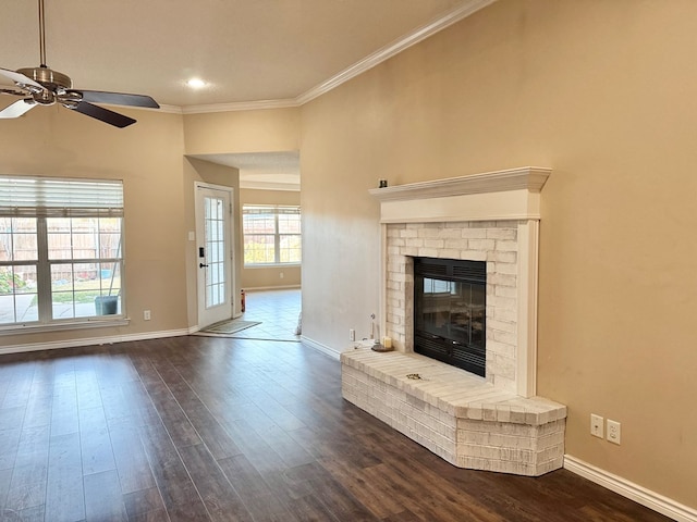 unfurnished living room with crown molding, ceiling fan, a fireplace, and dark wood-type flooring