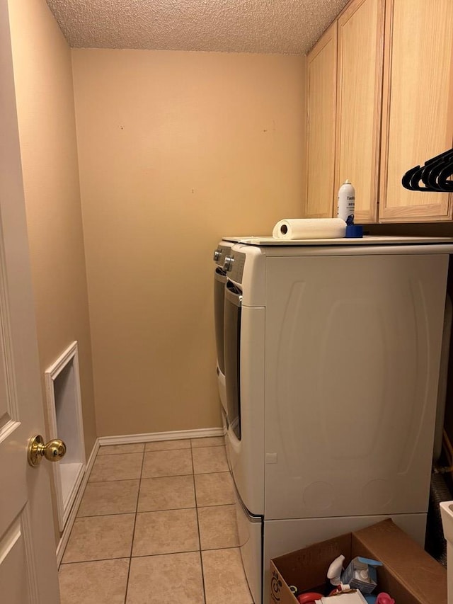 laundry area featuring separate washer and dryer, cabinets, a textured ceiling, and light tile patterned flooring